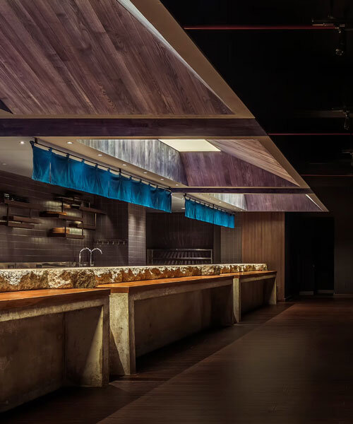 indigo fabric partitions float above sculpted concrete counters in rokusho bar by inrestudio