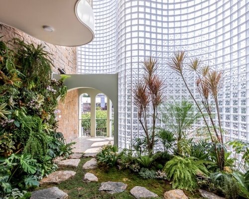 curved facade of 3,000 glass bricks wraps DA VÀNG studio's translucent house in vietnam